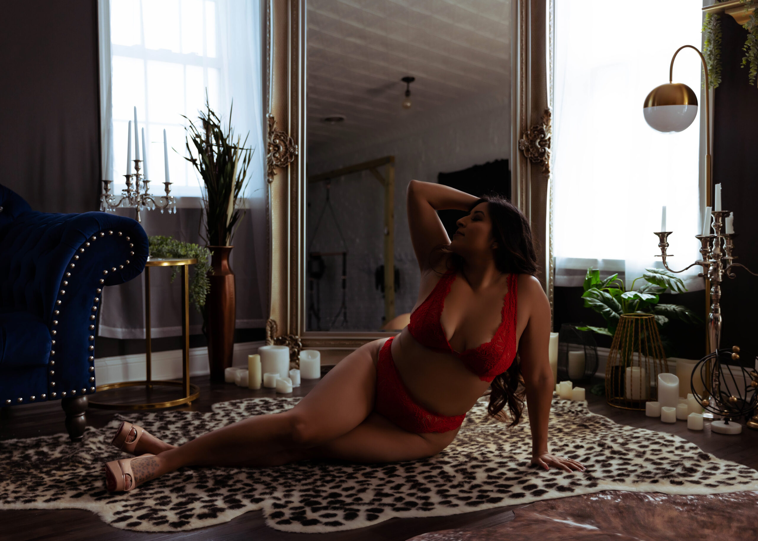 Black woman in red lingerie laying on floor and arching in front of mirror